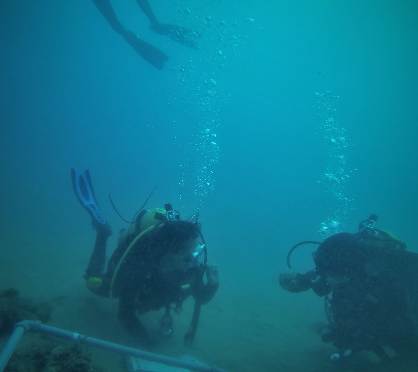 Two scuba divers working near the seabed with bubbles rising above them