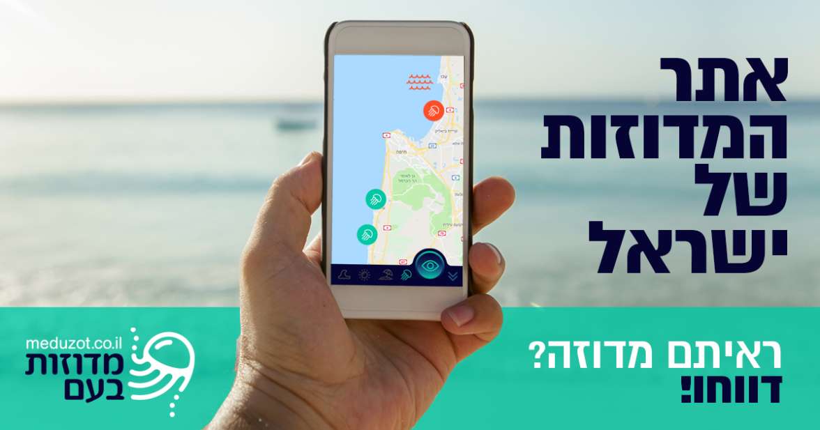 A hand holding a phone showing the Meduzot Ba'am jellyfish map, with the sea in the background